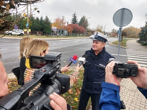 umundurowany policjant udziela wywiadu mediom, w tle skrzyżowanie.