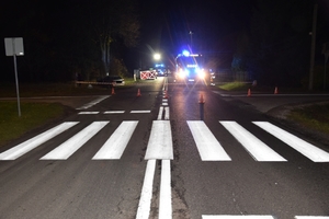 skrzyżowanie ulic, miejsce wypadku, widoczny samochód który uderzył w drzewo.  Dalej kotara zabezpieczająca oraz służby ratunkowe.