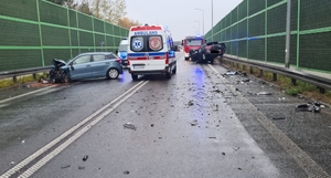 miejsce zdarzenia drogowego dwóch osobówek na drodze krajowej 74, na miejscu uszkodzone pojazdy oraz służby ratunkowe.