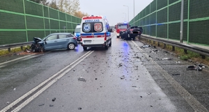 miejsce zdarzenia drogowego dwóch osobówek na drodze krajowej 74, na miejscu uszkodzone pojazdy oraz służby ratunkowe.