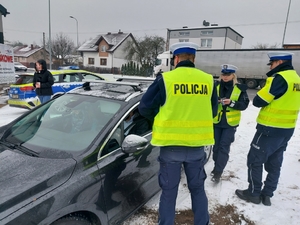 policjanci w czasie kontroli drogowej i działań profilaktycznych, przekazują kierowcy zawieszkę samochodową w kształcie serduszka z napisem zwolnij jak kocha to poczeka.