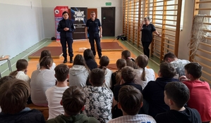 policjanci i ratownik medyczny na spotkaniu z uczniami w szkole.