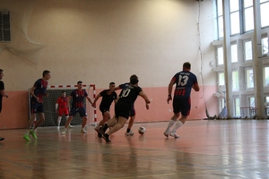mężczyźni zawodnicy w czasie gry w piłkę nożną na hali sportowej.