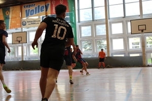 mężczyźni zawodnicy w czasie gry w piłkę nożną na hali sportowej.