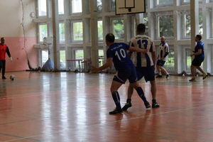 mężczyźni zawodnicy w czasie gry w piłkę nożną na hali sportowej.
