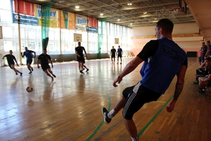 mężczyźni zawodnicy w czasie gry w piłkę nożną na hali sportowej.