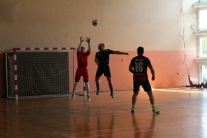 mężczyźni zawodnicy w czasie gry w piłkę nożną na hali sportowej.