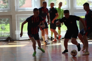 mężczyźni zawodnicy w czasie gry w piłkę nożną na hali sportowej.