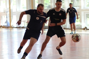 mężczyźni zawodnicy w czasie gry w piłkę nożną na hali sportowej.