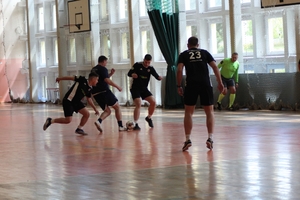 mężczyźni zawodnicy w czasie gry w piłkę nożną na hali sportowej.