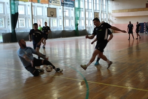 mężczyźni zawodnicy w czasie gry w piłkę nożną na hali sportowej.
