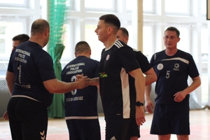 mężczyźni zawodnicy w czasie gratulacji na hali sportowej.