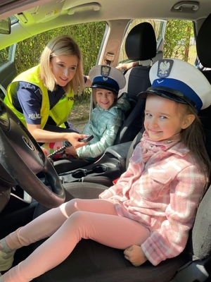 policjantka pokazuje dzieciom radiowóz. dzieci siedzą w radiowozie.