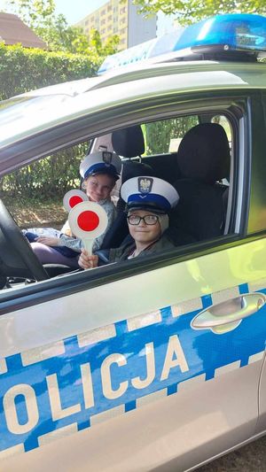 dwoje przedszkolaków siedzi w radiowozie, wszystko w wyniku spotkania policjantów z dziećmi w szkole.