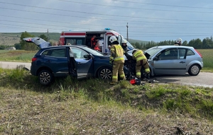 wypadek drogowy z udziałem dwóch pojazdów osobowych, na miejscu pracują strażacy oraz medycy, na zdjęciu uszkodzone pojazdy po zderzeniu czołowym, przy nich stoi karetka pogotowia.