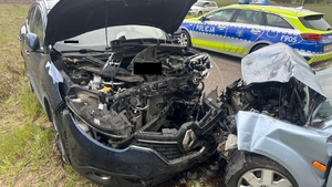 widok dwóch pojazdów uszkodzonych po zderzeniu czołowym, obok stoi radiowóz policyjny.