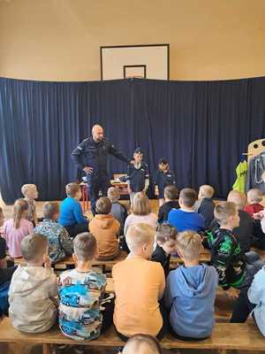 policjant na spotkaniu z uczniami, prowadzi lekcję o ich bezpieczeństwie.