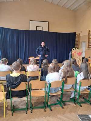 policjant na spotkaniu z uczniami, prowadzi lekcję o ich bezpieczeństwie.