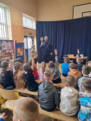 policjant na spotkaniu z uczniami, prowadzi lekcję o ich bezpieczeństwie.