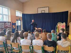 policjant na spotkaniu z uczniami, prowadzi lekcję o ich bezpieczeństwie.