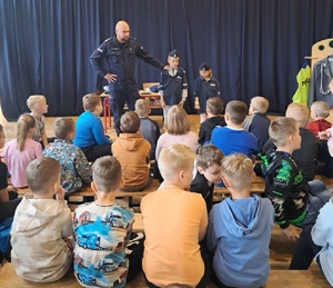 policjant na spotkaniu z uczniami, prowadzi lekcję o ich bezpieczeństwie.