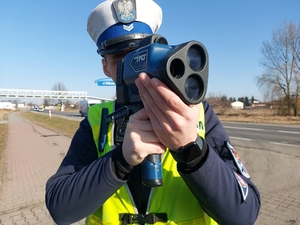 policjant trzyma urządzenie do pomiaru prędkości.