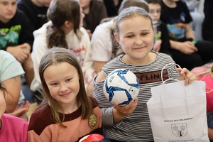 na zdjęciu uśmiechnięte dziewczynki, jedna z nich trzyma nagrodę.
