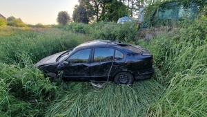 widok pojazdu po dachowaniu, auto stoi na kołach na trawiastym podłożu, jest uszkodzone.