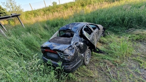 widok pojazdu po dachowaniu, auto stoi na kołach na trawiastym podłożu, jest uszkodzone.