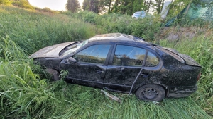 widok pojazdu po dachowaniu, auto stoi na kołach na trawiastym podłożu, jest uszkodzone.