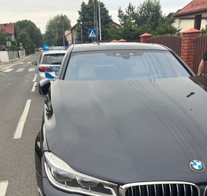 pojazd marki bmw , sprawca kolizji drogowej , stoi na poboczu drogi, dalej radiowóz, który widać częściowo.