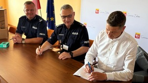 spotkanie dwóch policjantów oraz burmistrza. panowie siedzę przy stole  podpisuj dokumenty.