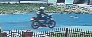 zdjęcie z monitoringu posesji, które przedstawia jadącego motocyklem po drodze.
