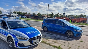 policjanci pełniący służbę w terenie, radiowóz samochód osobowy przy drodze.