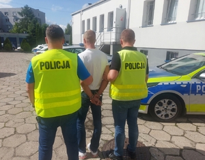 policjanci prowadzą zatrzymanego mężczyznę.