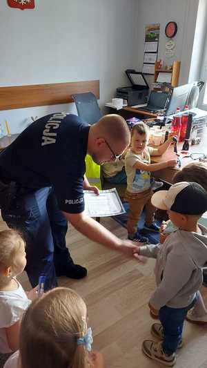 policjant w pomieszczeniu służbowym rozmawia z dziećmi, które odwiedziły posterunek Policji.