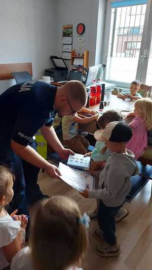 policjant w pomieszczeniu służbowym rozmawia z dziećmi, które odwiedziły posterunek Policji.