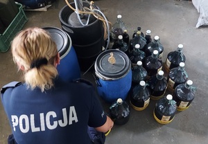 policjantka w czasie oględzin zabezpieczonego nielegalnego alkoholu, zdjęcie zrobione w pomieszczeniu służbowym komendy Policji.