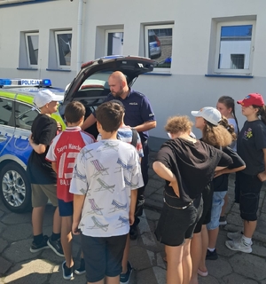 policjant pokazuje dzieciom radiowóz.