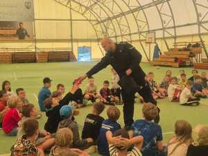 policjant na spotkaniu z dziećmi uczestniczącymi w półkoloniach.