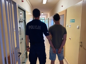 Umundurowany policjant prowadzi zatrzymanego mężczyznę. zdjęcie zrobione na korytarzu komendy.