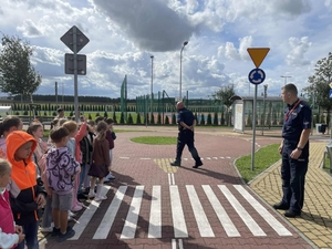 policjanci uczą dzieci prawidłowych zachowań na przejściu dla pieszych.
