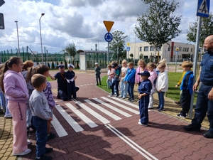 policjanci uczą dzieci prawidłowych zachowań na przejściu dla pieszych.