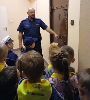 policjant pokazuje przedszkolakom pomieszczenie służbowe w posterunku policji.
