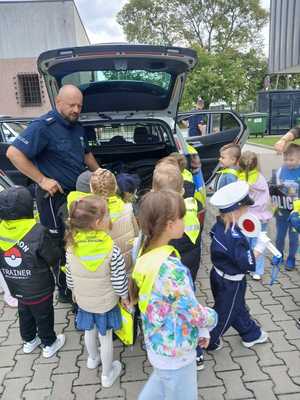 policjant pokazuje przedszkolakom radiowóz policyjny.