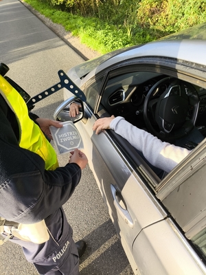 policjantka wręcza kierowcy ulotkę.