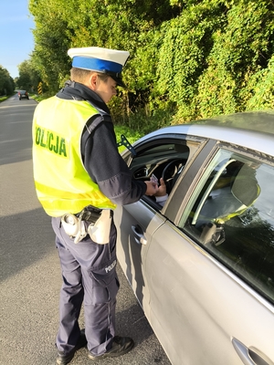 policjantka wręcza kierowcy ulotkę.