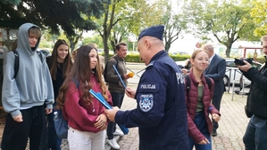 zdjęcie z akcji Odblaski ratują życie, która była wspólną akcją Policji i Starostwa Powiatowego w ramach kampanii „Bezpieczna droga do szkoły”. Na zdjęciu Komendant i Starosta Bełchatowski,  przed budynkiem szkoły. Komendant i Starosta rozdają uczniom odblaski.