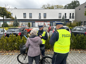 policjanci wręczają opaskę odblaskową rowerzystce.
