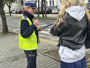 policjantka wręcza opaskę odblaskową kobiecie.